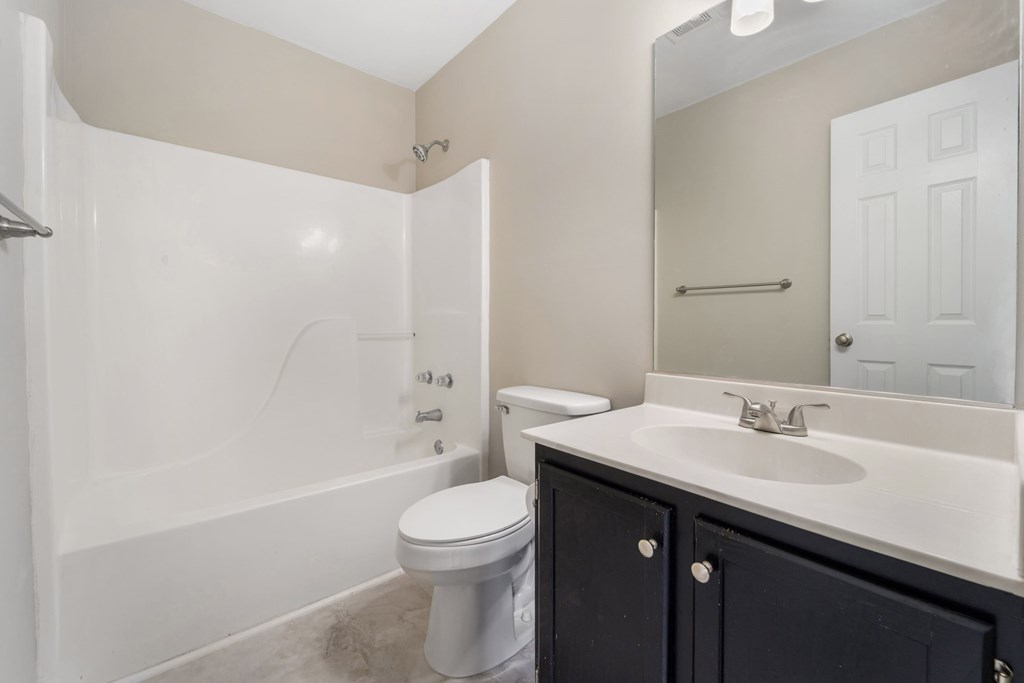 A white toilet sits in a bathroom next to a sink.