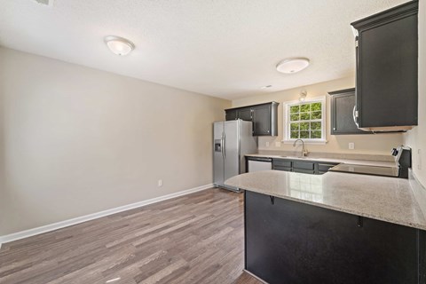 A kitchen with a black counter and a refrigerator.