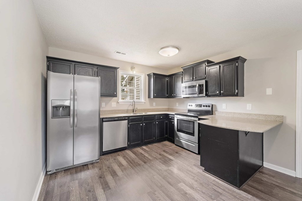 A kitchen with black cabinets and stainless steel appliances.