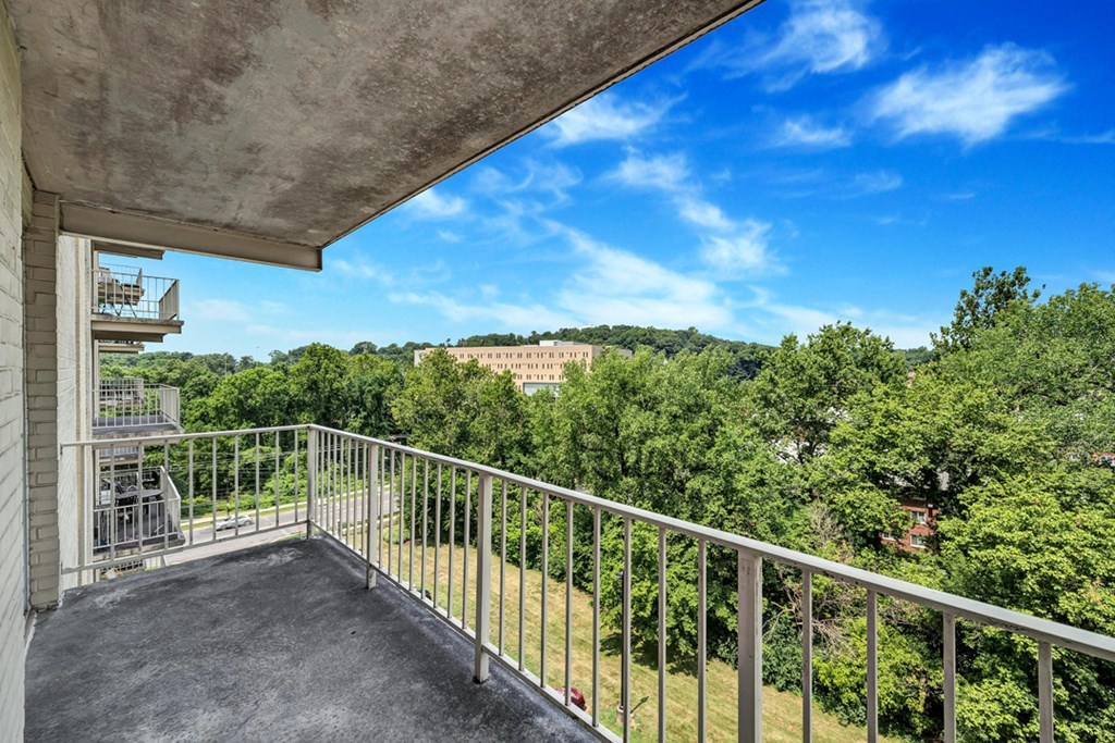 a balcony with a view of trees and a blue sky