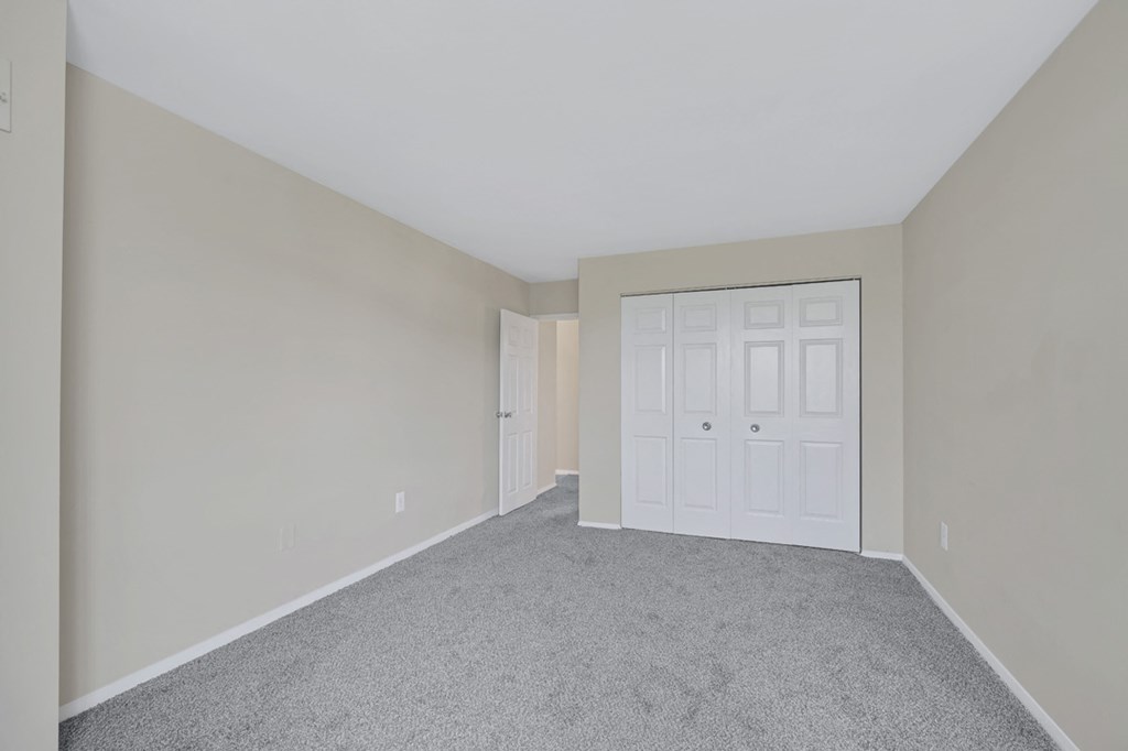 an empty bedroom with a white door and carpet