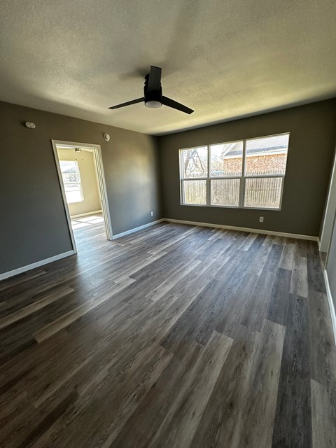 an empty living room with wood floors and a ceiling fan