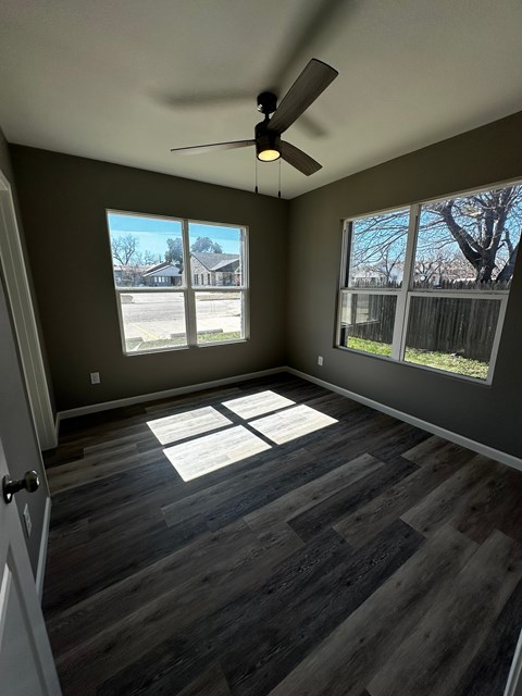 an empty living room with wood floors and a ceiling fan