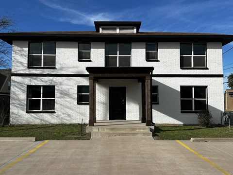 a white brick building with a porch and a black door
