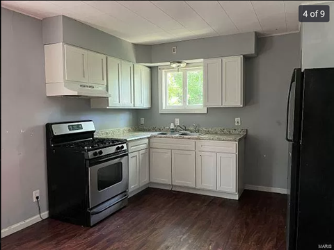 a kitchen with white cabinets and a stove and a sink