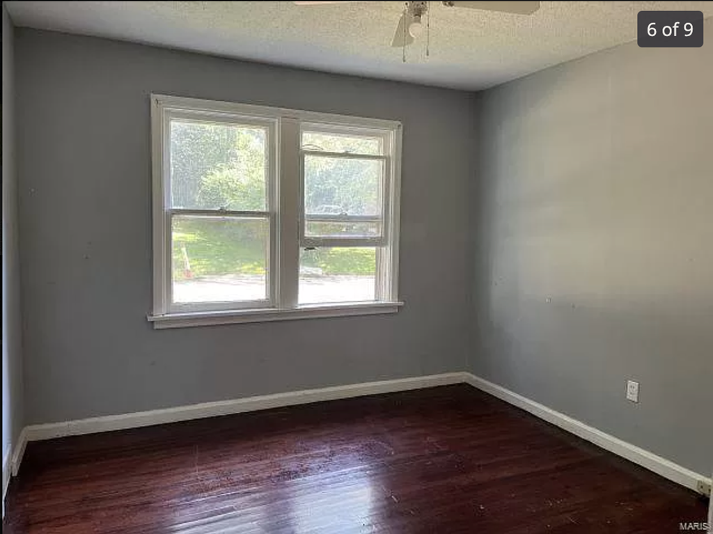 a empty room with a window and wooden floors