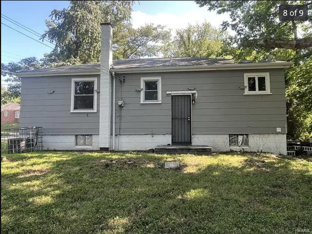 a small gray house with a yard and grass