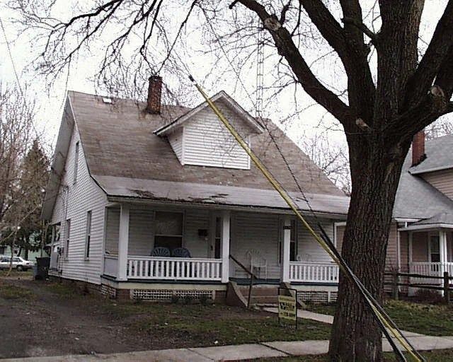 a white house with a porch and a tree