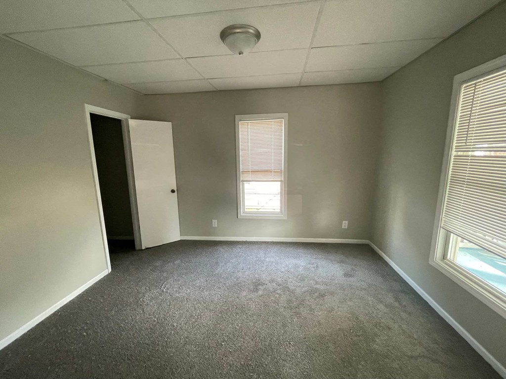 an empty room with two windows and a door