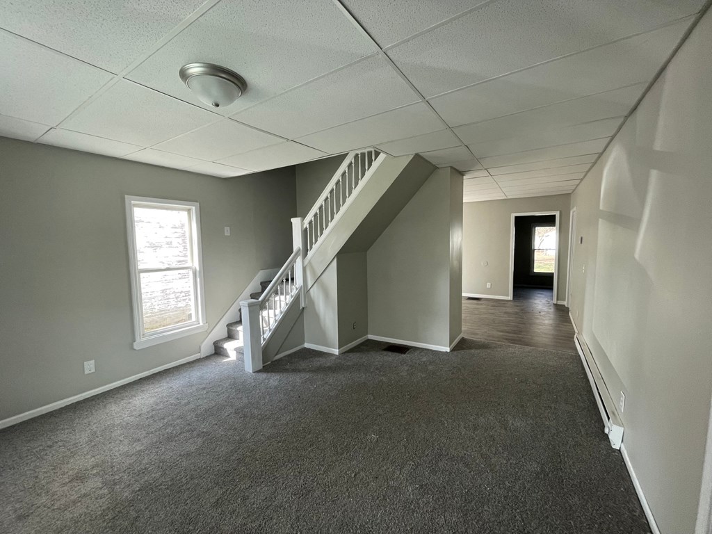an empty living room with a staircase and a window