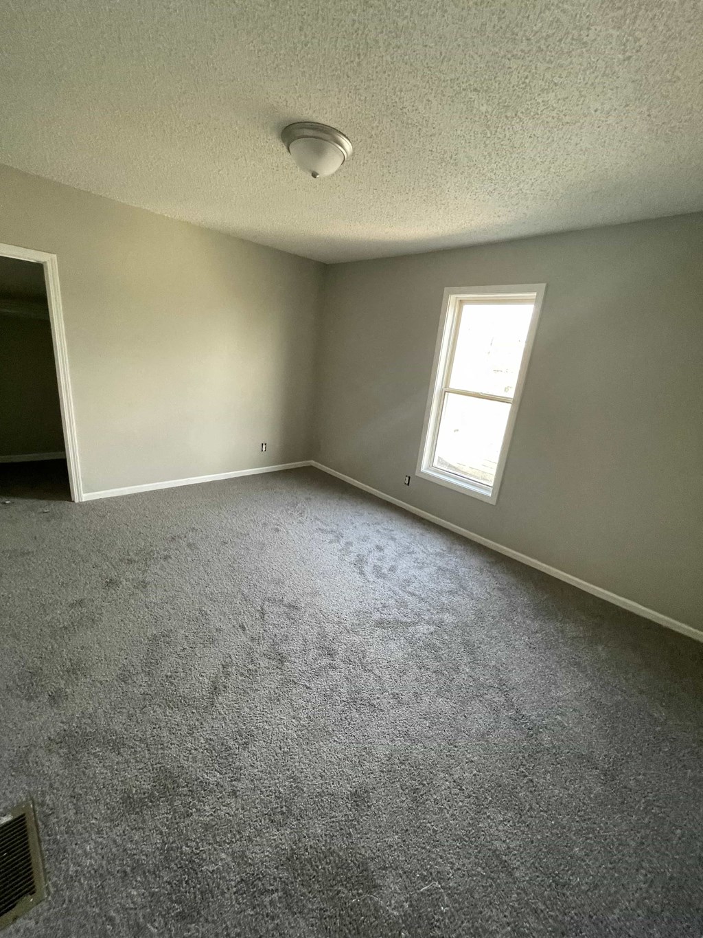 an empty living room with a window and carpet