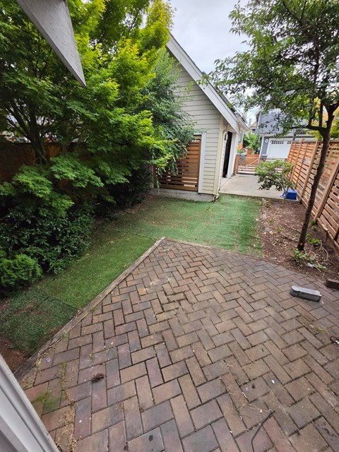A backyard with a brick walkway and a small house.