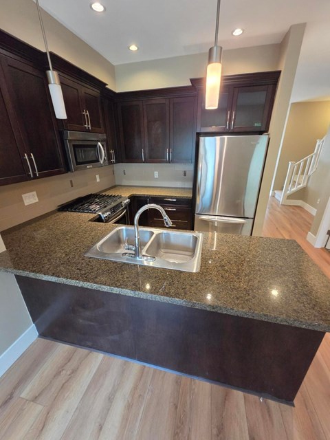 A kitchen with a granite countertop and stainless steel appliances.
