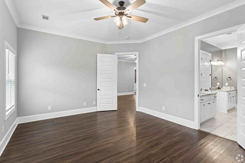 A room with a ceiling fan and wooden flooring.