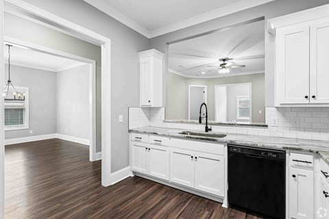 A kitchen with white cabinets and a black dishwasher.