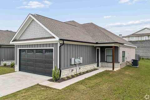 A modern house with a grey garage door and a brown roof.