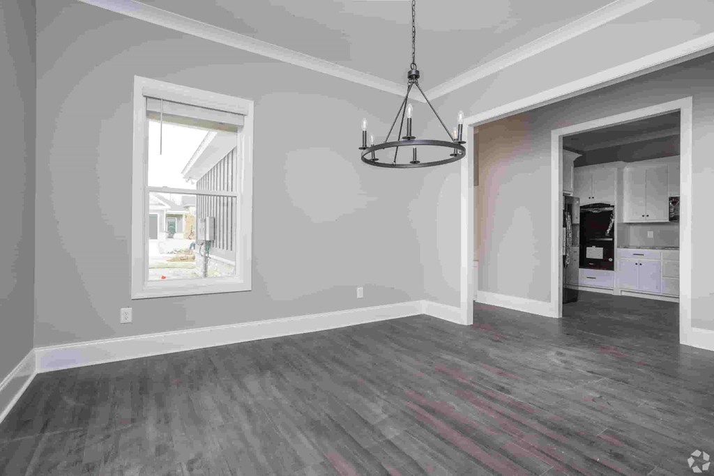A room with a grey floor and a chandelier hanging from the ceiling.