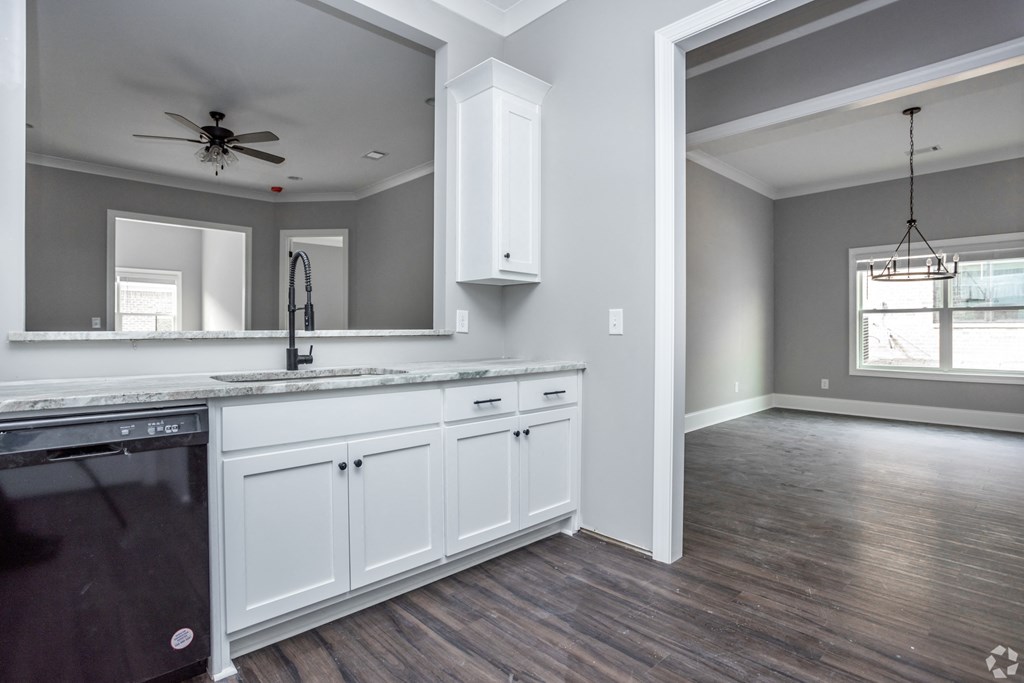 A kitchen with white cabinets and a black dishwasher.