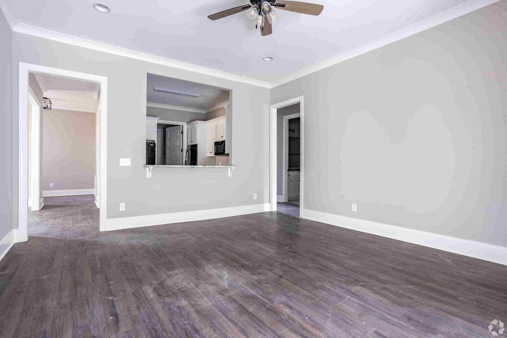 A room with a ceiling fan and wood flooring.
