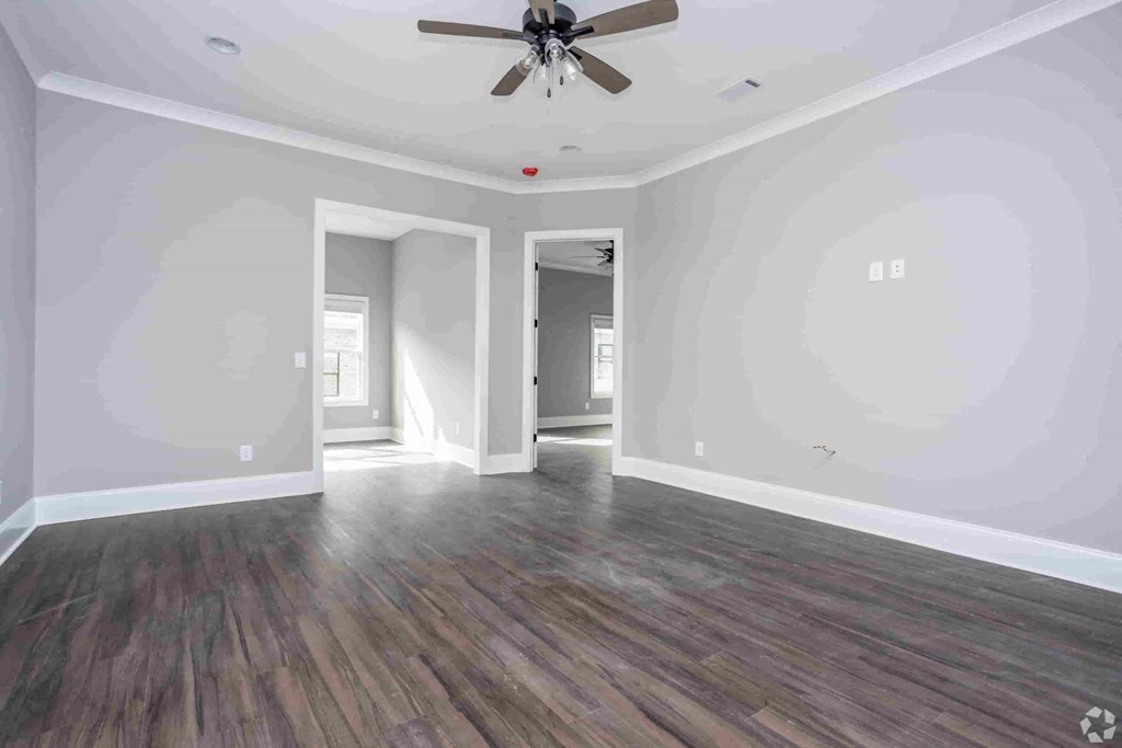 A room with a ceiling fan and wood flooring.