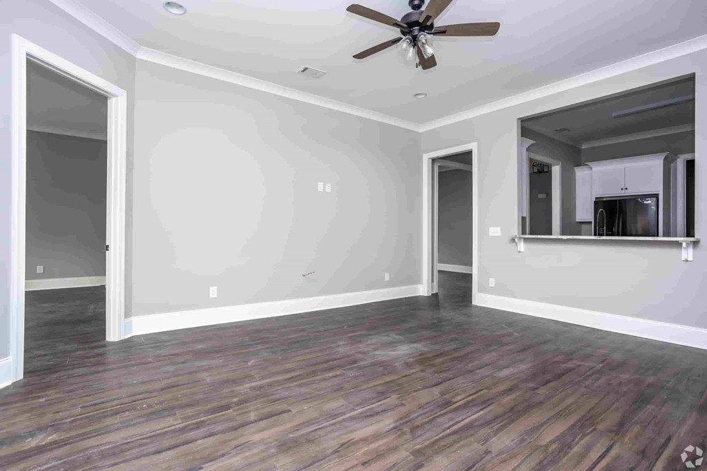 A room with a ceiling fan and wood flooring.