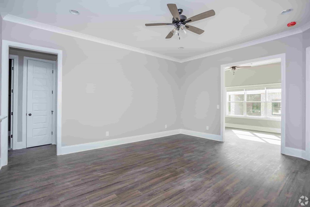 A room with a ceiling fan and wooden flooring.