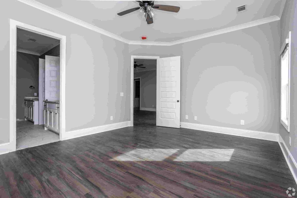 A room with a ceiling fan and a doorway leading to another room.