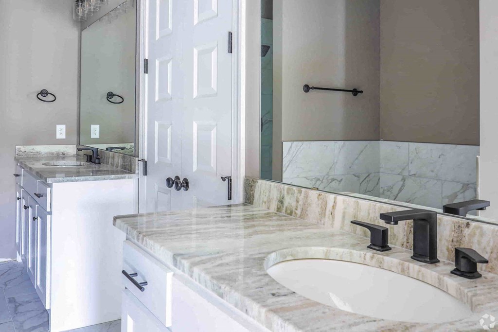 A bathroom with a marble countertop and a white sink.