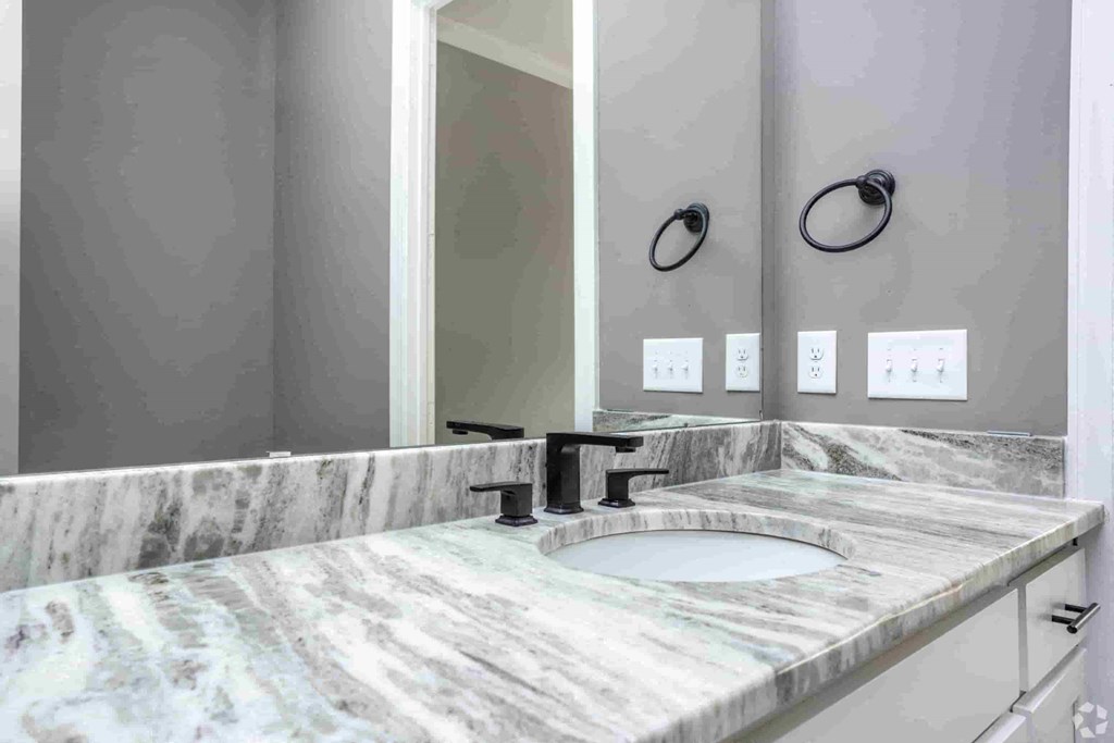 A bathroom with a marble countertop and a large mirror.