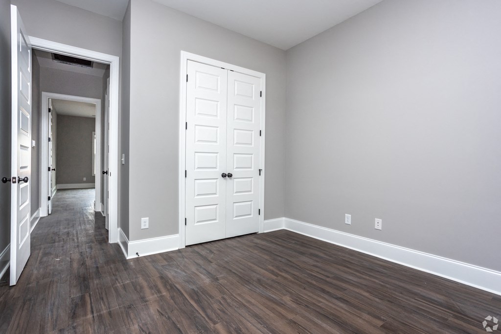 A room with a white door and a wooden floor.
