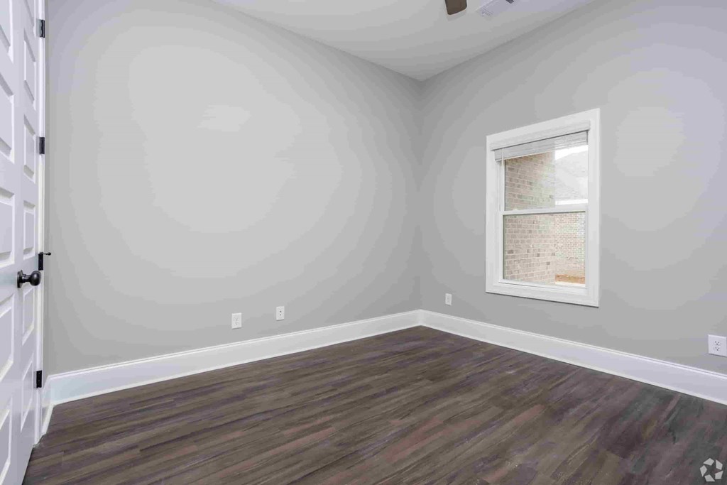 A room with a wooden floor and a window with a white frame.