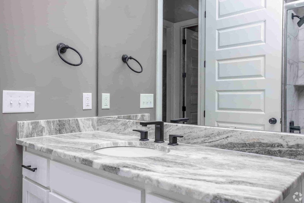 A bathroom with a marble countertop and a white door.