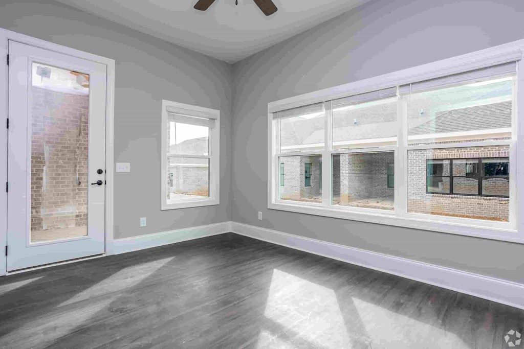 A room with a white door, grey walls, and a window with a view of a brick building.