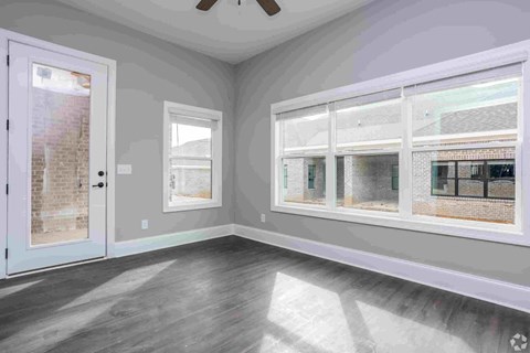 A room with a white door, grey walls, and a window with a view of a brick building.