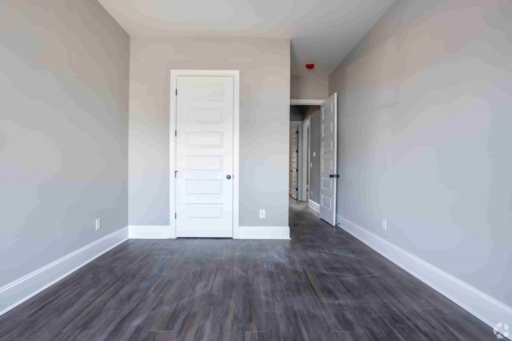A room with a white door and wooden flooring.