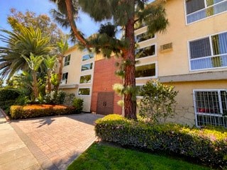 an apartment building with a sidewalk and trees in front of it