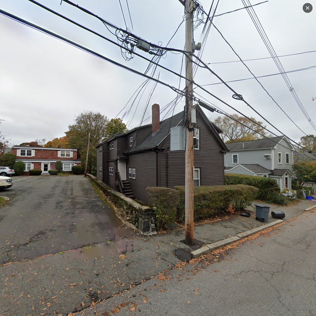 a house on the corner of a street with power lines