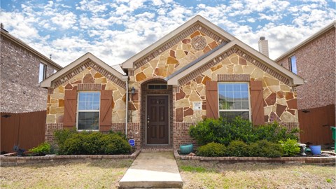 a brick house with a brown door and a cloudy sky
