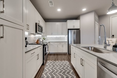 an open kitchen with white cabinets and stainless steel appliances