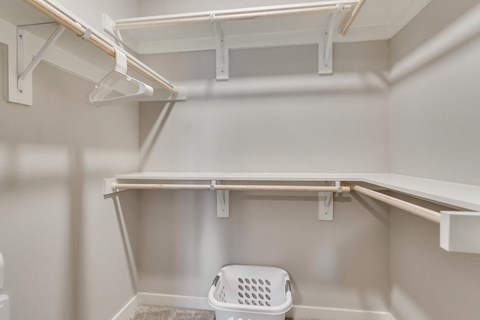 a walk in closet with shelves and a laundry basket