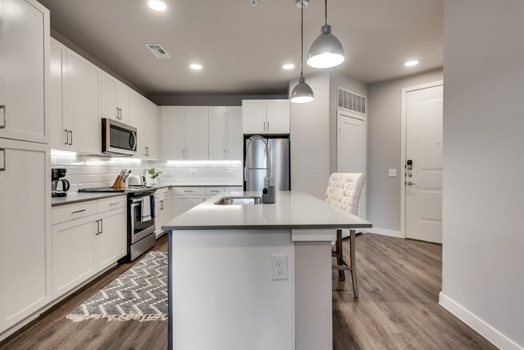 an open kitchen and dining area with white cabinets and stainless steel appliances