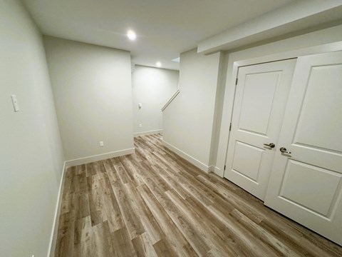 a bedroom with white walls and white doors and wood flooring