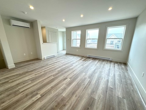 an empty living room with hardwood floors and a large window