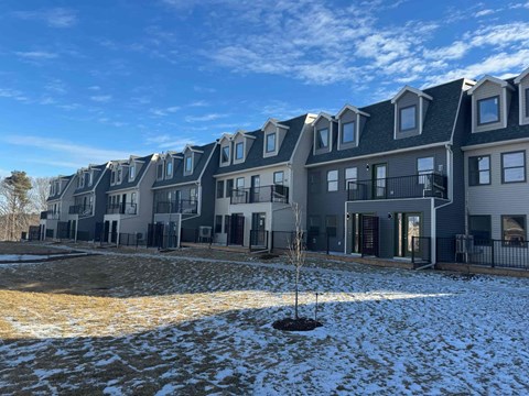 a snow covered yard in front of a row of houses