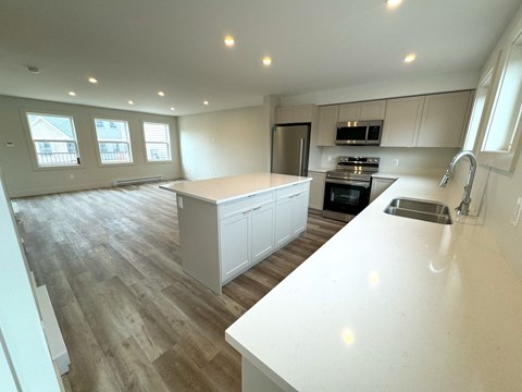 an open kitchen and living room with a large island and a sink