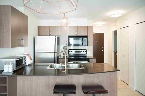 A modern kitchen with a refrigerator, microwave, oven, and sink.