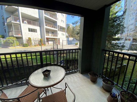 A balcony with a table and chairs overlooking apartment buildings.