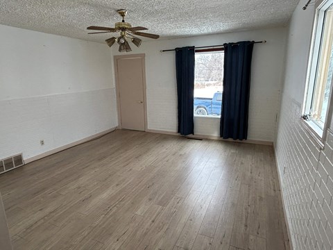 a living room with a ceiling fan and a window with a curtain