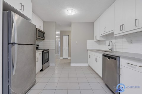 A kitchen with white cabinets and a stainless steel refrigerator.