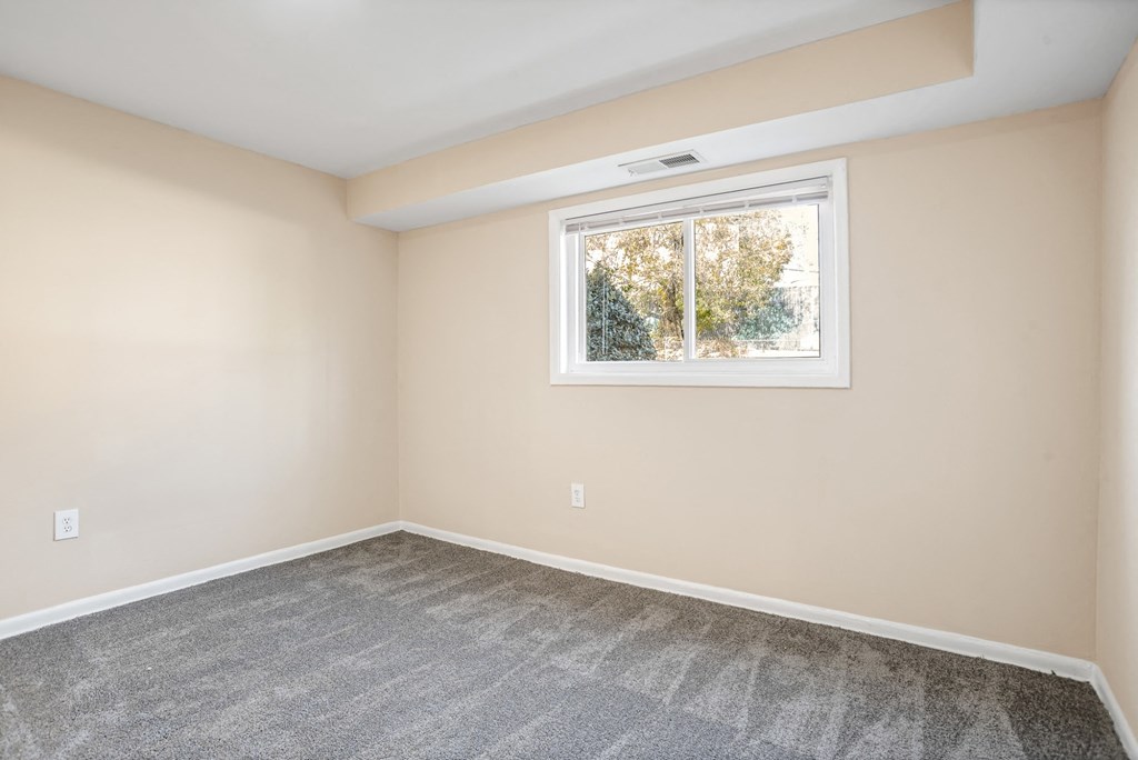A room with a window and carpeted floor.